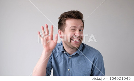 European young man waves his hand, greets his friends. 104021049