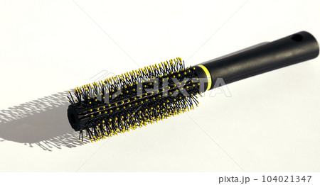 Round black hairbrush on a white background. Hair care concept. Round black hairbrush on a white background. Hair care concept. 104021347