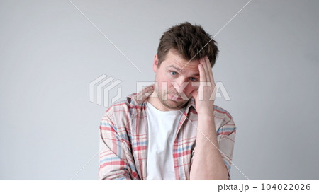 The European young man suffers from a headache and rubs his temples. 104022026