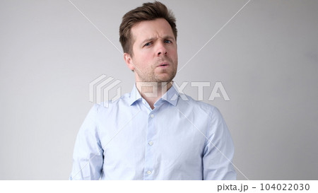 man listens to the news with disbelief and looks astonished into the camera 104022030