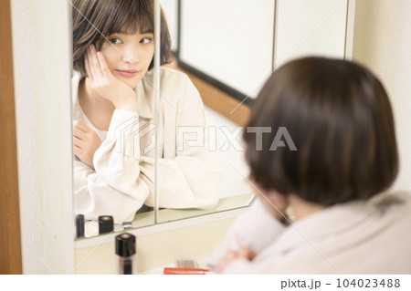メイクをする女性の鏡越しのポートレート メイクをする女性の鏡越しのポートレート 104023488