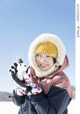 雪山で雪だるまを作って遊ぶ若い女性 104025114
