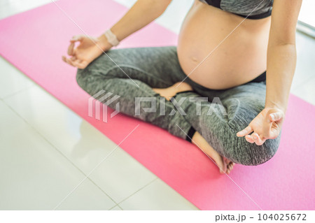 Young pregnant woman doing yoga exercises and meditating at home or yoga studio. Health care, mindfulness, relaxation and wellness concept Young pregnant woman doing yoga exercises and meditating at home or yoga studio. Health care, mindfulness, relaxation and wellness concept 104025672