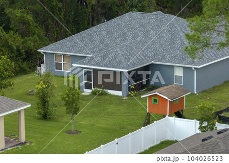 White vinyl picket fence on green lawn surrounding property grounds for backyard protection and privacy White vinyl picket fence on green lawn surrounding property grounds for backyard protection and privacy 104026523