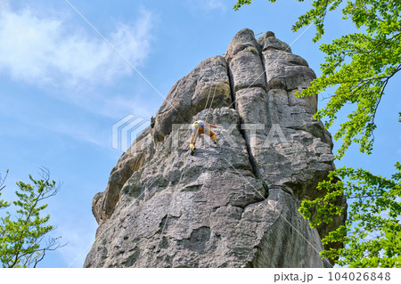 Strong male climber climbing steep wall of rocky mountain. Sportsman overcoming difficult route. Engaging in extreme sports hobby concept. Strong male climber climbing steep wall of rocky mountain. Sportsman overcoming difficult route. Engaging in extreme sports hobby concept. 104026848