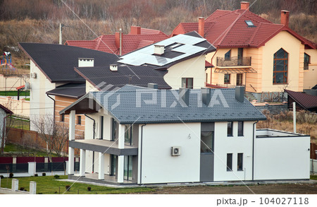 Residential houses with roof tops covered with metallic and ceramic shingles in rural suburban area 104027118
