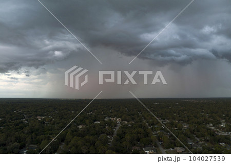 Landscape of dark ominous clouds forming on stormy sky before heavy thunderstorm over rural town area Landscape of dark ominous clouds forming on stormy sky before heavy thunderstorm over rural town area 104027539