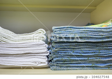 Interior of white plastic cabinet or clothing wardrobe with stacked pile of clean linen. Householding and order, furniture design concept. Interior of white plastic cabinet or clothing wardrobe with stacked pile of clean linen. Householding and order, furniture design concept. 104027548