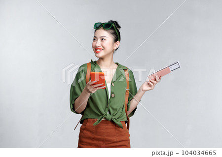 A young woman using cellphone while holding traveling tickets and passport isolated 104034665