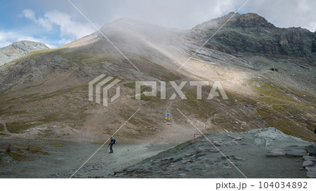 Hiker standing on a crossroad of paths in alpine environment, Austrian Alps, Europe Hiker standing on a crossroad of paths in alpine environment, Austrian Alps, Europe 104034892