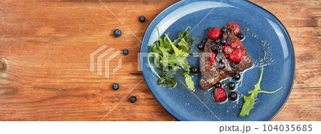 Beef steak in berry sauce on plate. 104035685