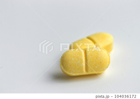 yellow color pill of vitamin c for children on white background, selective focus, close up 104036172