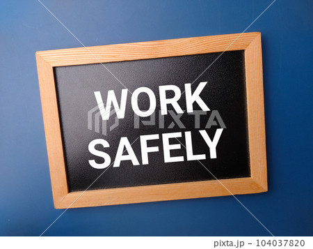 Black wooden board with the word WORK SAFELY on a blue background. 104037820