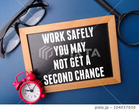Black wooden board with the word WORK SAFELY YOU MAY NOT GET A SECOND CHANCE on blue background. 104037830