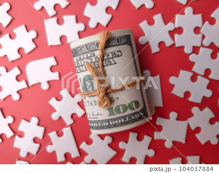 Top view banknotes and white puzzle on a red background Top view banknotes and white puzzle on a red background 104037884