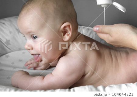 Mother Giving Massage To Little Child. Closeup. Mom Gives massage To Infant Baby. Prevention of Tremor. Female Hands Gently Massaging To Newborn Naked Body. Smears with Cream, Body care concept. Mother Giving Massage To Little Child. Closeup. Mom Gives massage To Infant Baby. Prevention of Tremor. Female Hands Gently Massaging To Newborn Naked Body. Smears with Cream, Body care concept. 104044523