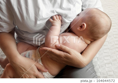 Mother breastfeeding baby at home. Mom nursing infant nurturing. Portrait of Child suckling milk from breast. Authentic shot of mother is breastfeeding her newborn baby Close Up. Concept of maternity 104044572
