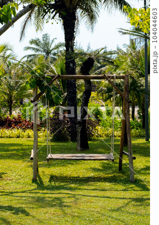 Hanging swing on backyard against palm trees. Summertime mood. 104044603