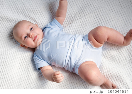 Portrait of Newborn. Beautiful Baby Face Close up. Small Child smiles and laughs. Cute little Baby is looking into the Camera. Newborn Health. Infancy, Childhood, and Health Concept 104044614