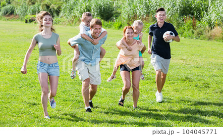 Smiling mother and father with four kids on green lawn Smiling mother and father with four kids on green lawn 104045771