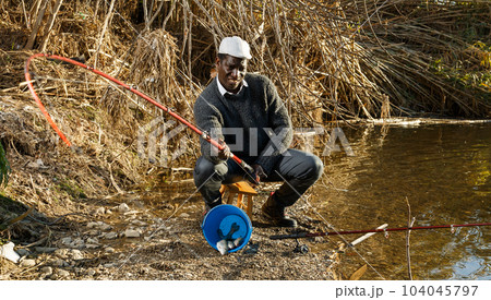 Man pulling fish with rods on river 104045797