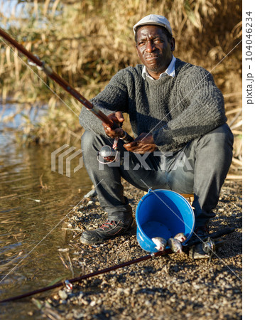 Fisherman sitting on wooden stool 104046234