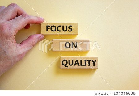 Focus on quality symbol. Concept words Focus on quality on blocks on beautiful white table white background. Businessman hand. Business, focus on quality concept. Copy space. Focus on quality symbol. Concept words Focus on quality on blocks on beautiful white table white background. Businessman hand. Business, focus on quality concept. Copy space. 104046639