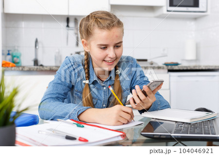Girl doing home task using mobile phone 104046921