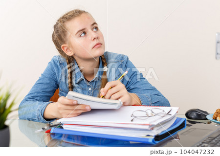 Girl doing her homework with laptop Girl doing her homework with laptop 104047232