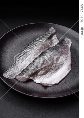 Raw sea bass fish fillet with salt, spices and herbs on a ceramic plate Raw sea bass fish fillet with salt, spices and herbs on a ceramic plate 104047663