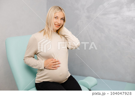 Young pregnant woman sitting on the gynecological chair during a medical consultation with gynecologist. 104047928
