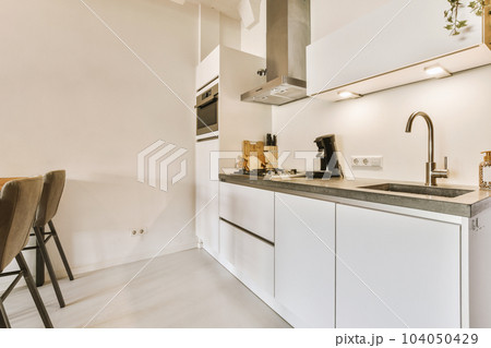 a kitchen with white cabinets and black counter tops on the island in front of the sink is next to the dining table 104050429