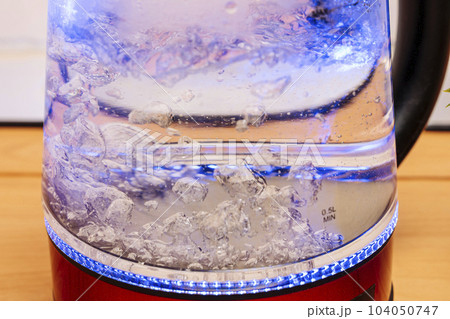 red modern boiling glass electric kettle close-up with bubbling water 104050747