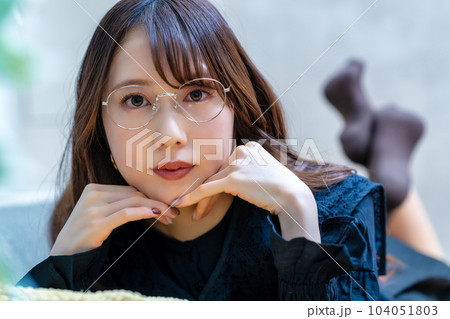 寝転んで寛ぐ眼鏡の若い女性 104051803