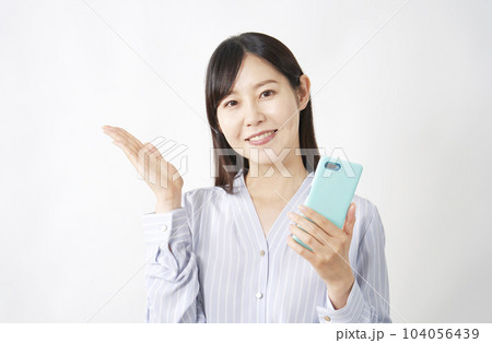 スマートフォンを持って左側を案内するミドルエイジ女性　白背景 104056439