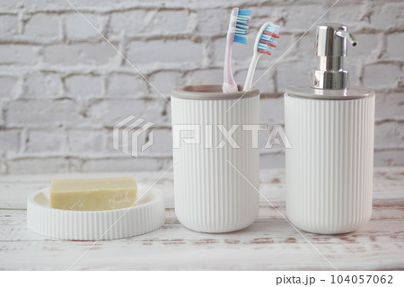 tooth brush in a white mug and soap on a case on table 104057062
