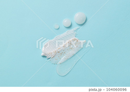 Some smears of skincare cosmetics product, lotion, cream or transparent. Cosmetic texture close-up on a blue background Some smears of skincare cosmetics product, lotion, cream or transparent. Cosmetic texture close-up on a blue background 104060096