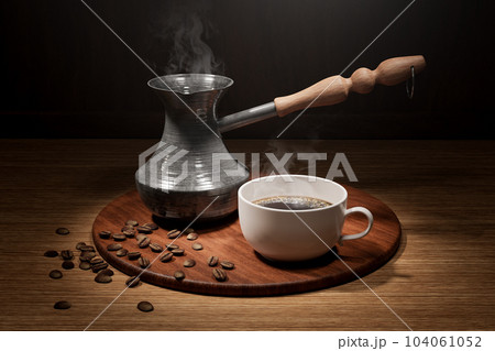 Turkish coffee cup. Coffee still life. Traditional turkish coffee. Cezve with coffee on wooden table 104061052