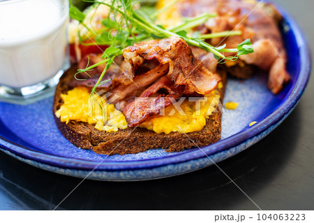 Very bright and healthy breakfast on a plate - bacon, egg, salad, tomato, cheese, a glass of yogurt. Close-up. Very bright and healthy breakfast on a plate - bacon, egg, salad, tomato, cheese, a glass of yogurt. Close-up. 104063223