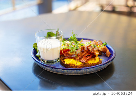 Very bright and healthy breakfast on a plate - bacon, egg, salad, tomato, cheese, a glass of yogurt. 104063224