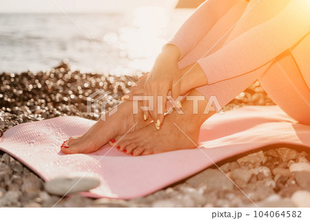 Woman sea yoga. Happy woman with black hair doing Pilates with the ring on the yoga mat near the sea on the pebble beach. Female fitness yoga concept. Healthy lifestyle, harmony and meditation. 104064582