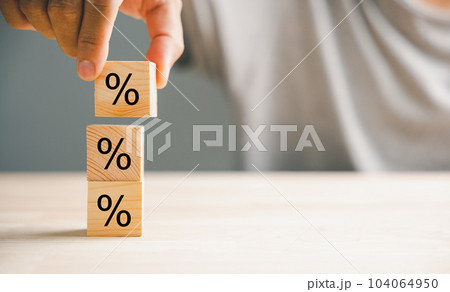 Concept of interest rate and financial rates. Hand placing a wooden cube block on top, symbolizing an increasing trend, with an upward direction icon and percentage symbol. 104064950