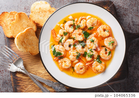 Gambas al ajillo or garlic shrimp is a traditional Spanish tapas made by combining fresh shrimp with an ajillo sauce. Horizontal top view 104065336