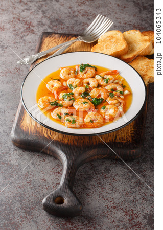 Spanish Garlic Shrimp Gambas al Ajillo closeup on the plate served with toasts. Vertical 104065343
