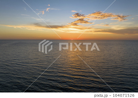 Dramatic bright red sky at ocean sunset, soft evening clouds over sea dark water 104071526