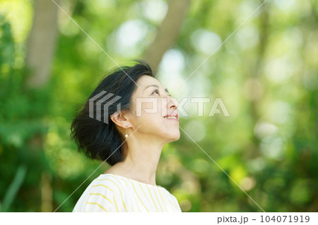 緑の中、白髪交じりの髪を風になびかせる中年女性 緑の中、白髪交じりの髪を風になびかせる中年女性 104071919