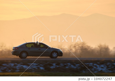 Car driving fast on intercity road at sunset. Highway traffic in evening 104072247