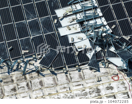 Broken down photovoltaic solar panels destroyed by hurricane Ian winds mounted on industrial building roof for producing green ecological electricity. Consequences of natural disaster Broken down photovoltaic solar panels destroyed by hurricane Ian winds mounted on industrial building roof for producing green ecological electricity. Consequences of natural disaster 104072285