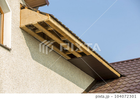 Bottom view detail of new modern house cottage corner with stucco walls, brown shingled roof and unfinished siding installation on clear blue sky copy space background. Real estate concept. 104072301