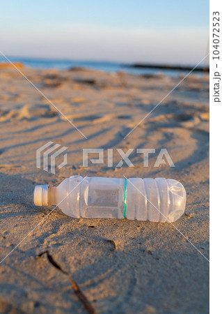 夕方の砂浜に捨てられたペットボトル 104072523